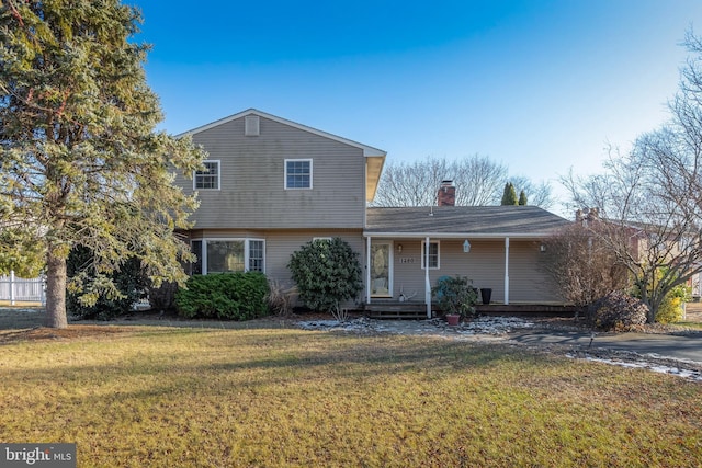 view of front of house with a porch, a chimney, and a front lawn