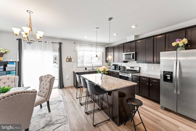 kitchen with appliances with stainless steel finishes, backsplash, dark brown cabinets, and light stone countertops