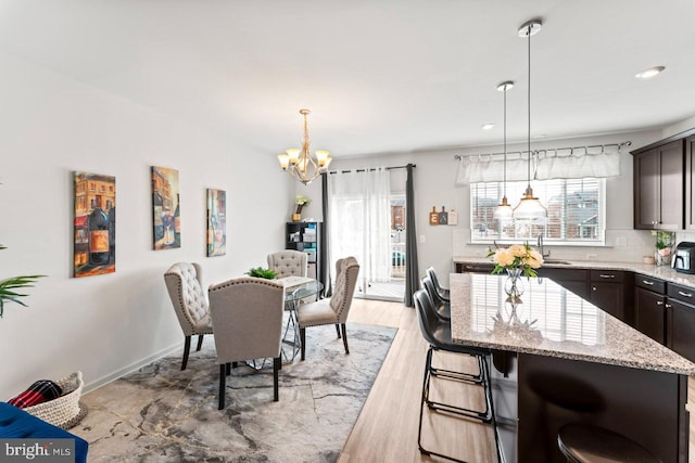 dining space featuring light wood-style floors, recessed lighting, a notable chandelier, and baseboards