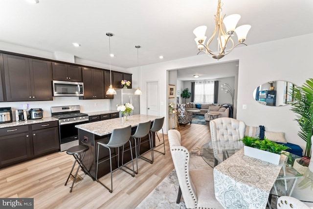 kitchen featuring light wood-style flooring, a breakfast bar area, stainless steel appliances, and dark brown cabinets