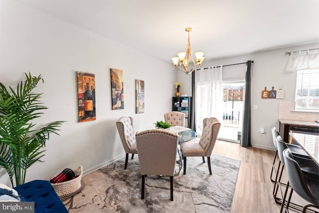 dining space featuring light wood finished floors, baseboards, and a chandelier