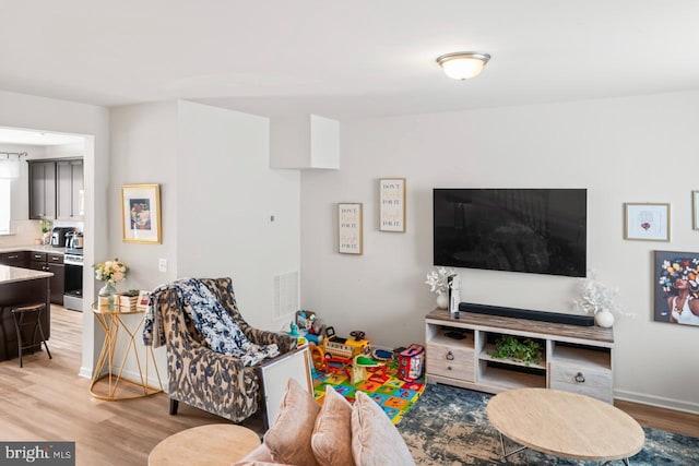 living room featuring light wood-style flooring, visible vents, and baseboards