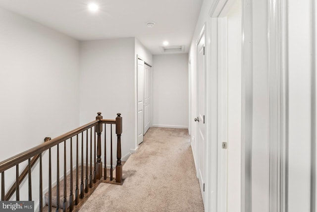 hall featuring carpet floors, visible vents, baseboards, an upstairs landing, and attic access