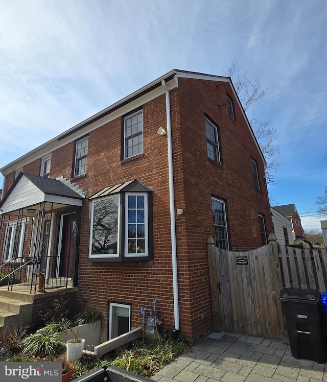 view of side of property with brick siding and fence