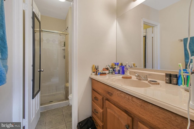 bathroom with tile patterned flooring, a stall shower, toilet, and vanity