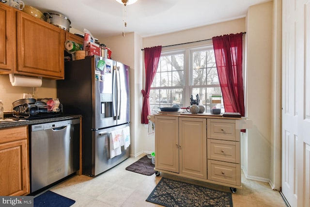 kitchen featuring baseboards, brown cabinets, dark countertops, and appliances with stainless steel finishes