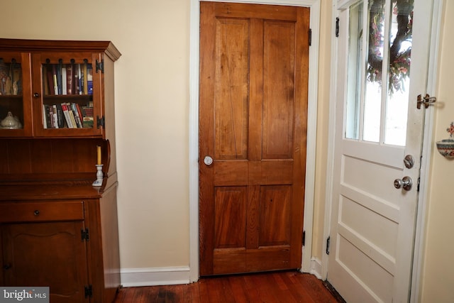 doorway to outside with dark wood-style floors and baseboards