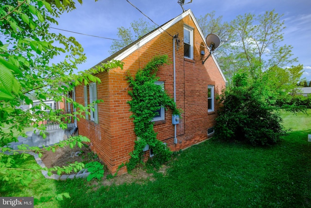 view of home's exterior with a lawn and brick siding