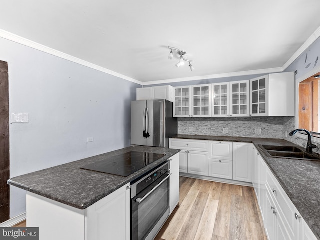 kitchen featuring light wood-style flooring, a sink, stainless steel appliances, crown molding, and tasteful backsplash