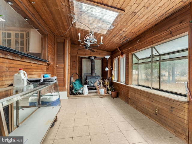 unfurnished sunroom featuring vaulted ceiling, a wood stove, wood ceiling, and a chandelier