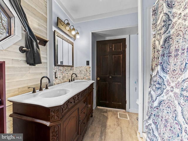 bathroom featuring double vanity, visible vents, wood finished floors, and a sink