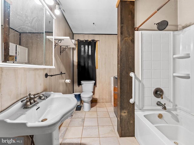 full bathroom featuring wooden walls,  shower combination, a sink, tile patterned floors, and toilet