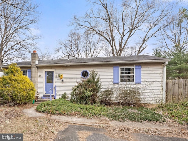 single story home featuring entry steps, fence, and a chimney