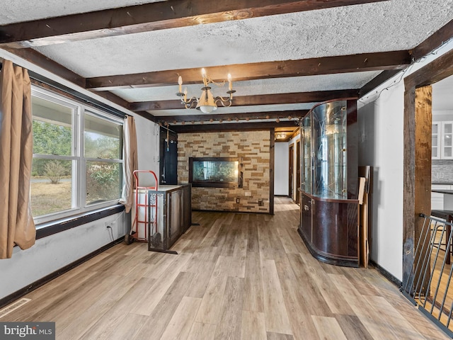 interior space with beam ceiling, wood finished floors, baseboards, and a textured ceiling