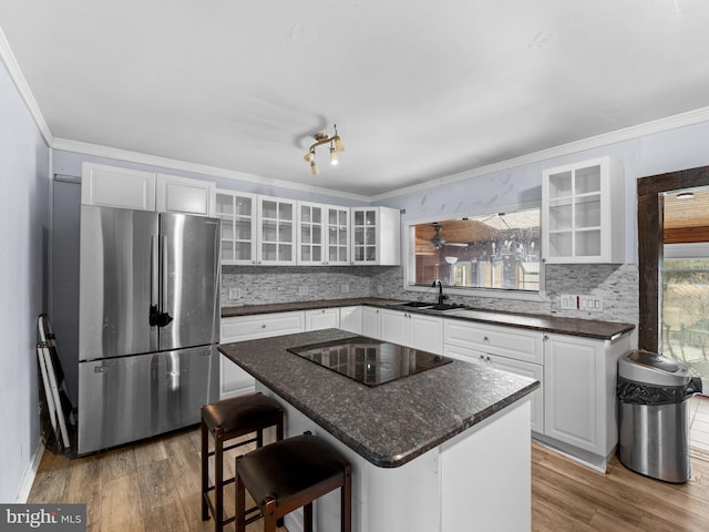 kitchen featuring black electric cooktop, wood finished floors, freestanding refrigerator, and ornamental molding