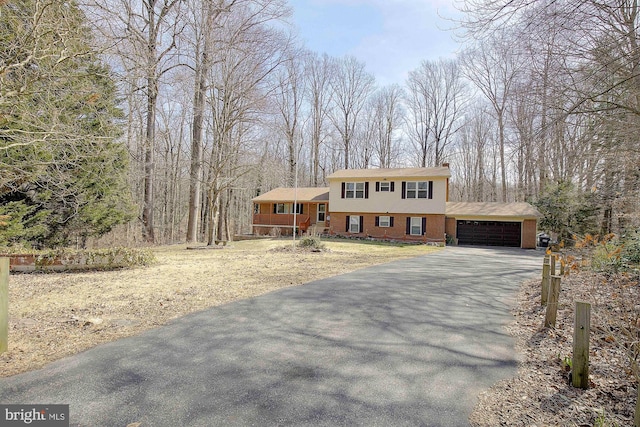 view of front of property featuring a garage, brick siding, and driveway