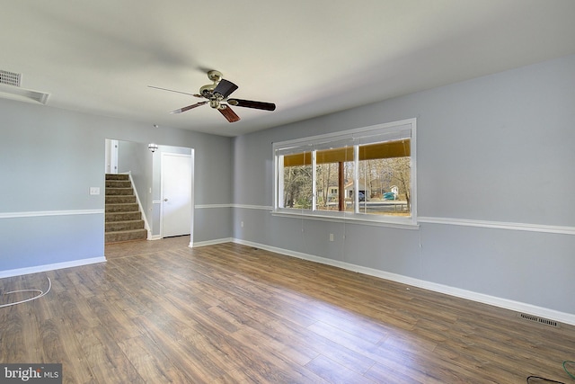 empty room featuring stairway, wood finished floors, visible vents, and baseboards