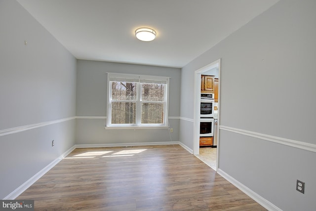 unfurnished dining area with baseboards and wood finished floors