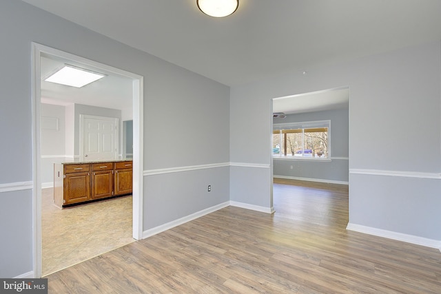 spare room with baseboards and light wood-type flooring