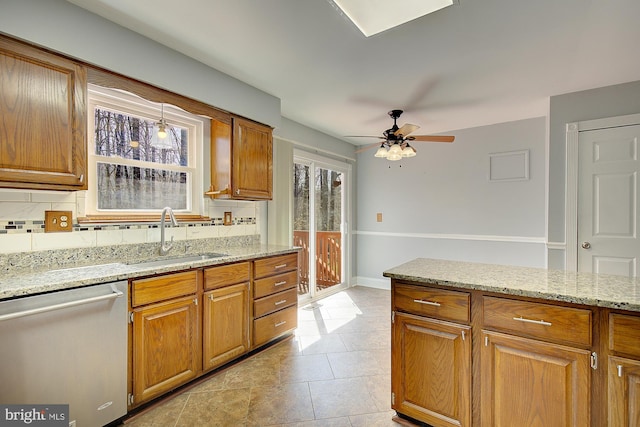 kitchen featuring backsplash, dishwasher, light stone counters, brown cabinets, and a sink