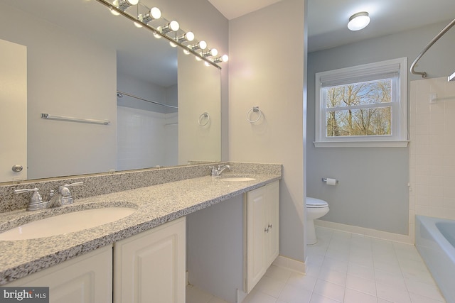 full bathroom with double vanity, toilet, baseboards, and a sink