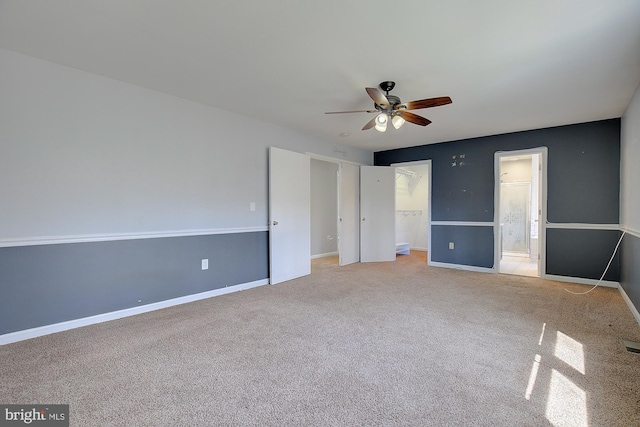 unfurnished bedroom featuring a walk in closet, baseboards, carpet, a closet, and ensuite bath