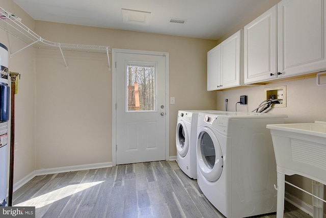 laundry room with light wood-type flooring, visible vents, cabinet space, separate washer and dryer, and baseboards