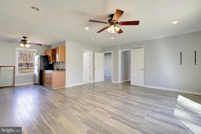 unfurnished living room featuring wood finished floors, visible vents, and baseboards