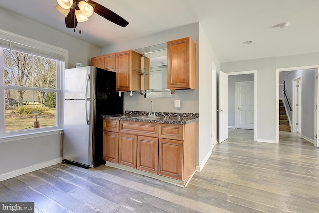 kitchen featuring a sink, brown cabinets, light wood finished floors, and freestanding refrigerator