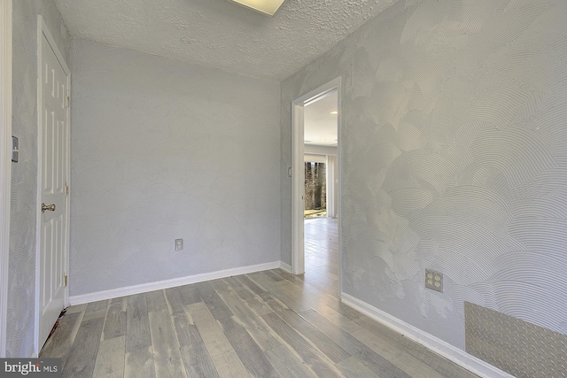 spare room with wood finished floors, baseboards, and a textured ceiling