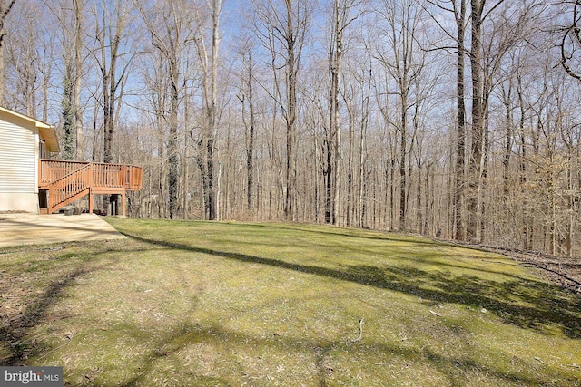 view of yard featuring stairway, a wooden deck, and a view of trees