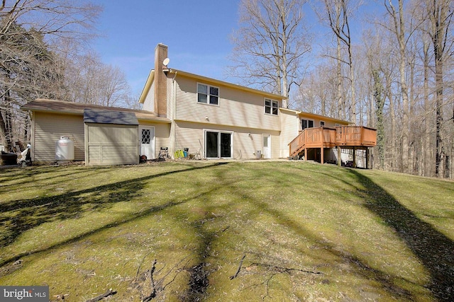 back of house featuring a lawn, a chimney, and a deck