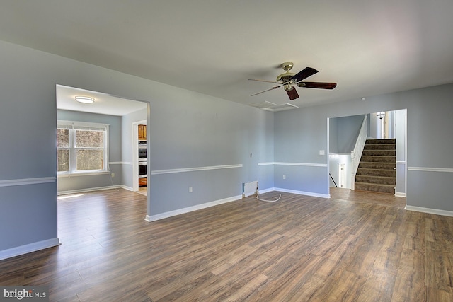 spare room featuring a ceiling fan, stairway, baseboards, and dark wood-style flooring