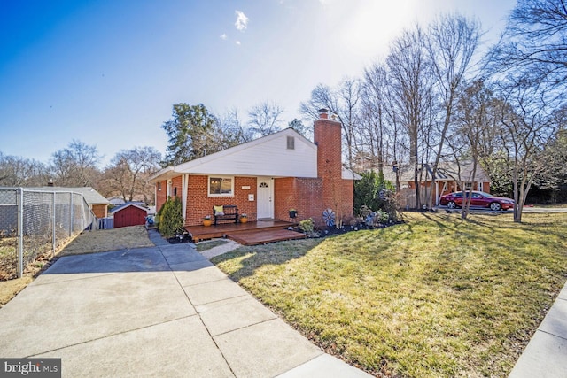 view of front facade featuring a front lawn, brick siding, fence, and an outdoor structure