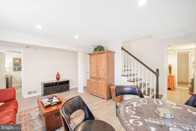 living room featuring light wood-style floors, recessed lighting, visible vents, and stairs