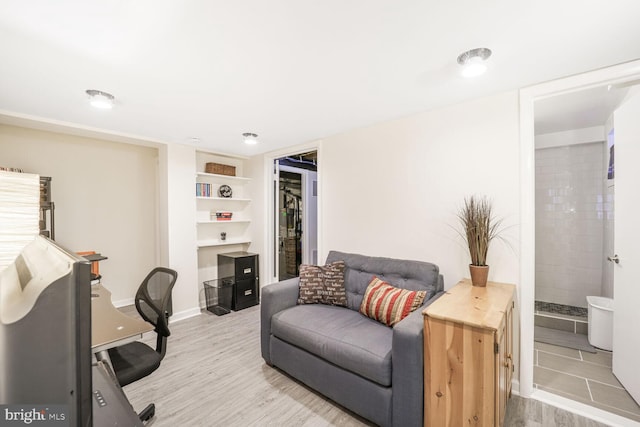 home office with wood finished floors, built in study area, and baseboards