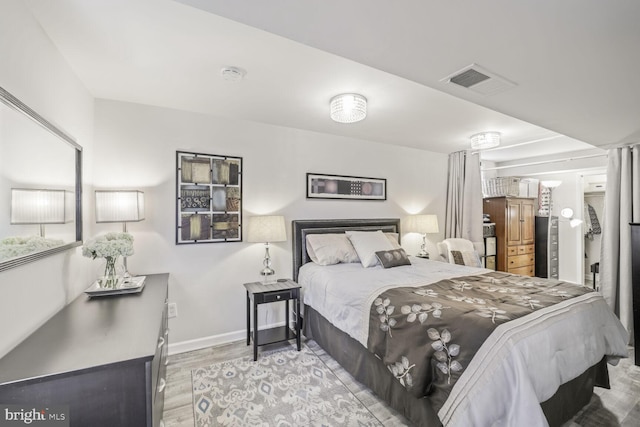 bedroom with wood finished floors, visible vents, and baseboards