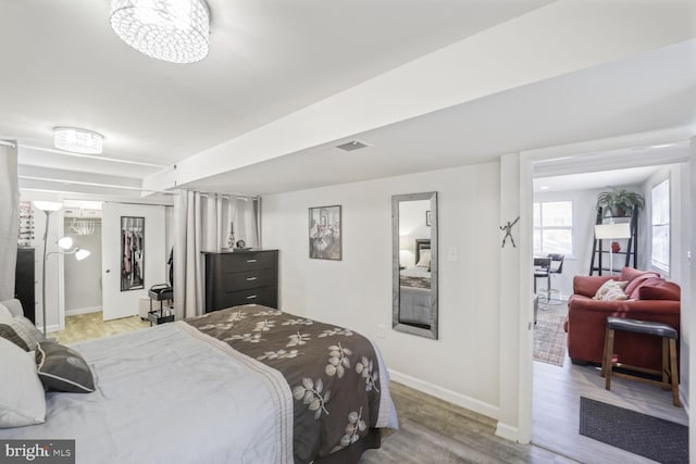 bedroom with a closet, visible vents, baseboards, and wood finished floors