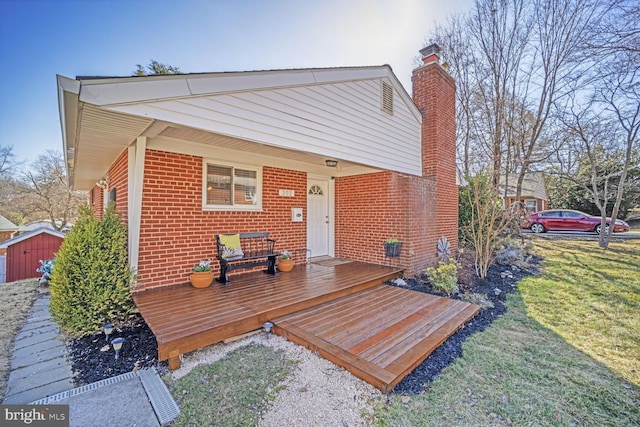 exterior space featuring a front yard, brick siding, and a deck