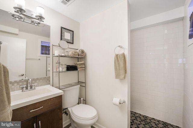 bathroom with visible vents, decorative backsplash, toilet, a tile shower, and vanity