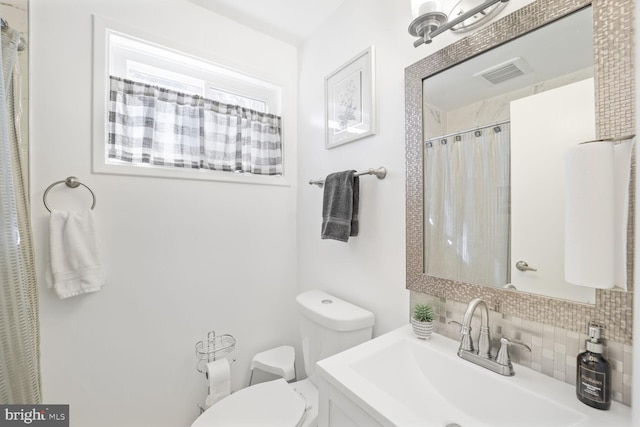 bathroom with visible vents, toilet, a sink, curtained shower, and backsplash