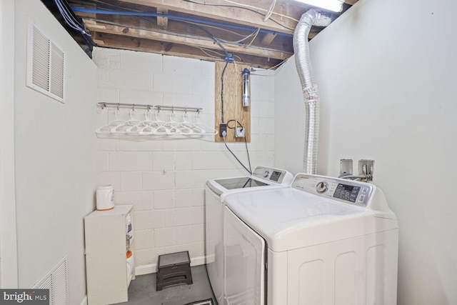 clothes washing area featuring washing machine and dryer, laundry area, and visible vents