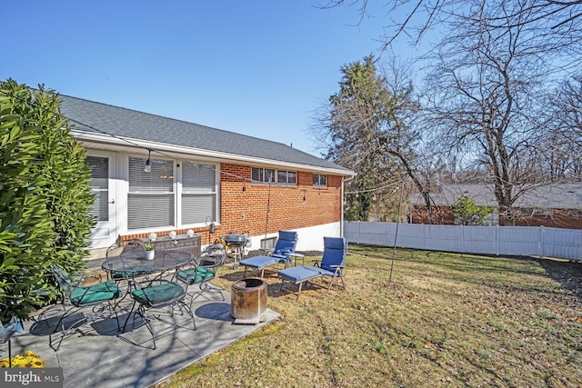 rear view of house featuring a patio area, a yard, fence, and brick siding