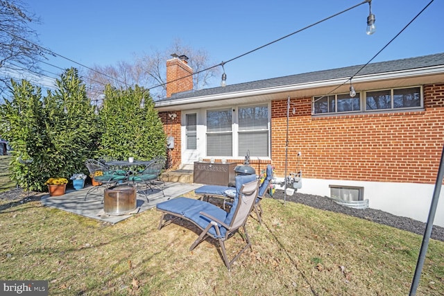 back of property featuring a patio area, brick siding, a lawn, and a chimney