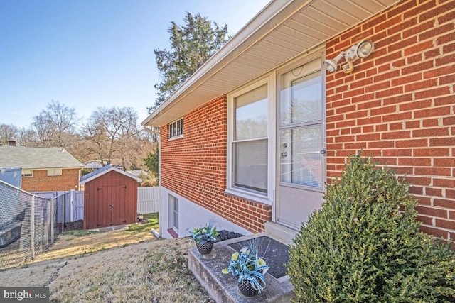 view of side of property featuring a shed, brick siding, an outdoor structure, and fence