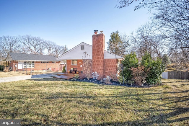 view of side of property with a lawn, a chimney, fence, a deck, and brick siding