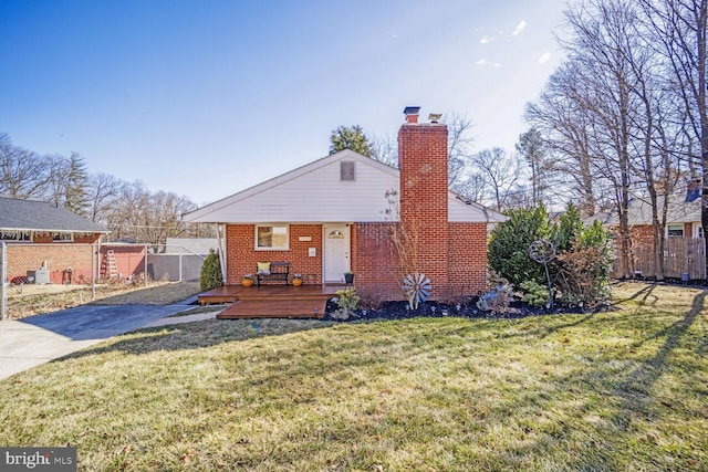 back of property featuring a yard, a chimney, fence, and brick siding