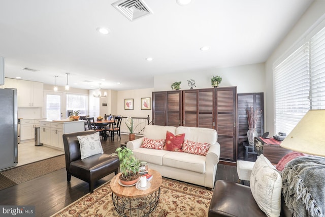 living room with a chandelier, light wood finished floors, visible vents, and recessed lighting