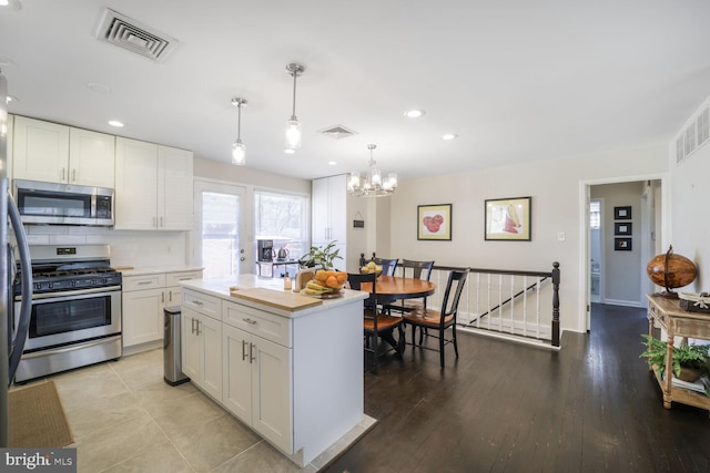 kitchen with white cabinetry, visible vents, stainless steel appliances, and decorative backsplash