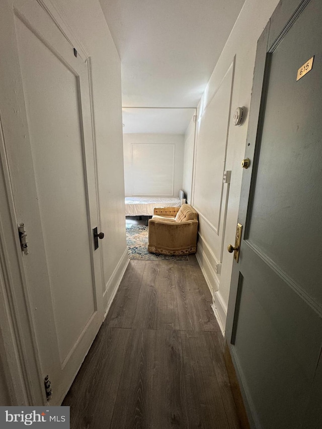 hall featuring dark wood-style floors and a decorative wall